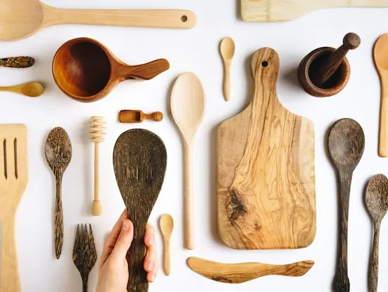Warning sign over black plastic kitchen utensils – highlighting the health and environmental risks of using plastic tools instead of safer wooden kitchen gadgets.