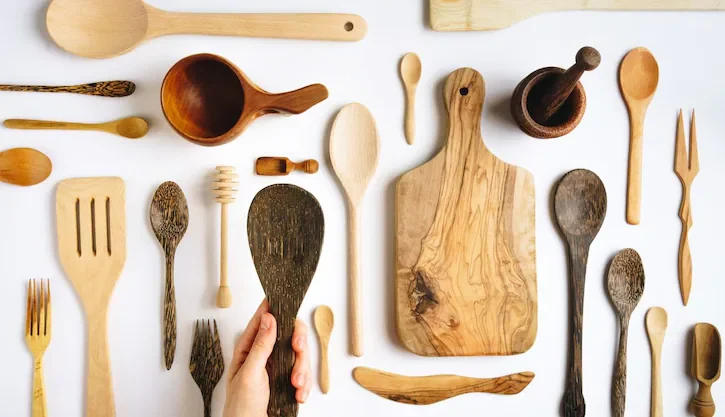 Warning sign over black plastic kitchen utensils – highlighting the health and environmental risks of using plastic tools instead of safer wooden kitchen gadgets.